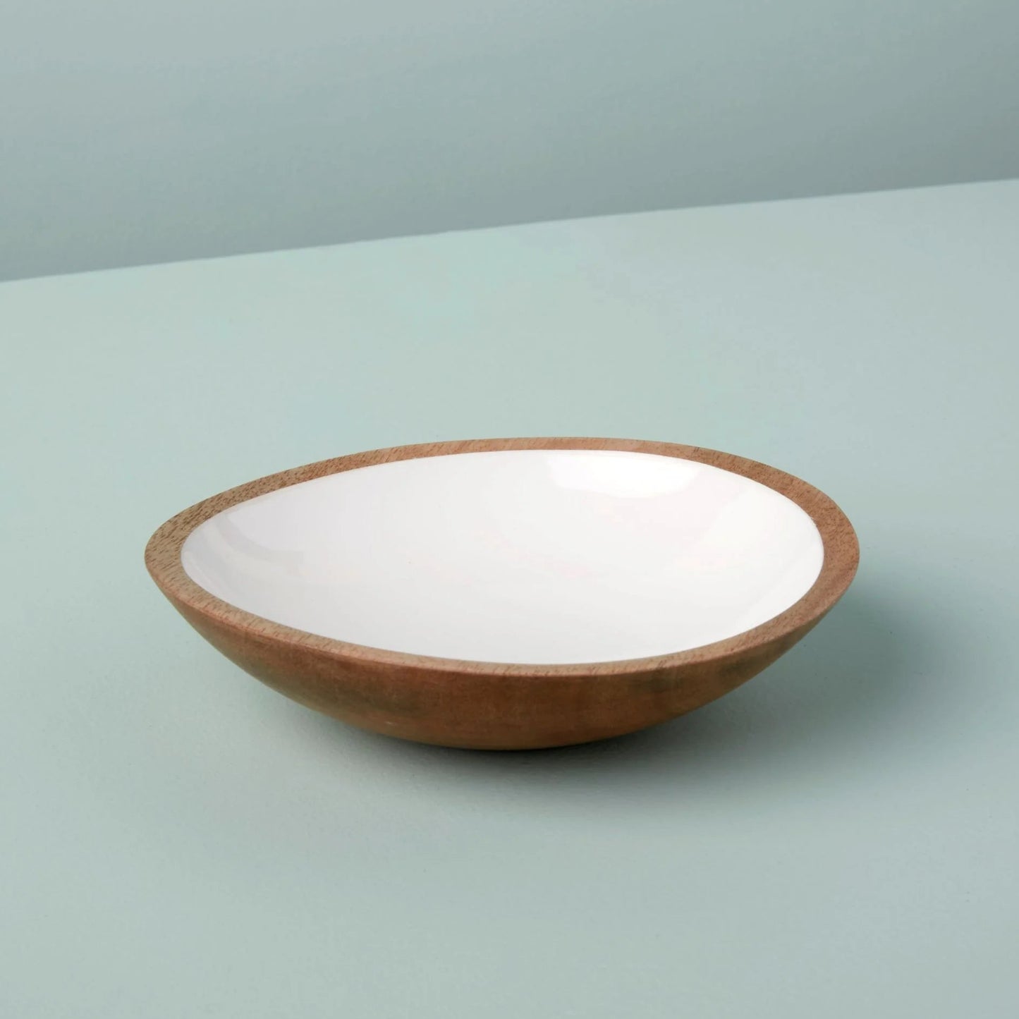 A oval-shaped, beige-colored, shallow wooden bowl with a white enamel coating on the inside, displayed against a light background.