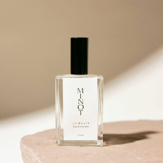 A clear glass bottle of Cliffwalk Room & Linen Spray with a black cap, labeled with the brand MINOT.